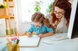 © Viacheslav Yakobchuk - Mother working remotely looking at daughter painting near her