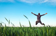 © es0lex - Young man jumping for joy over a green wheat field. Handsome farmer. Spring agriculture. Man admires the beauty of nature