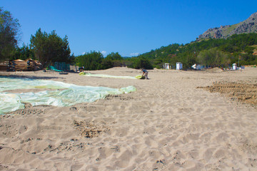 Rhodes, Greece, april 2019. Two men fold polyethylene on the beach, prepare the beach in the bay for the season