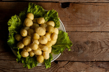 A plate of boiled new fresh potatoes on wooden background. Free space