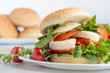© Igor Normann - Sandwich with mozzarella, tomato and salad on the kitchen table.
