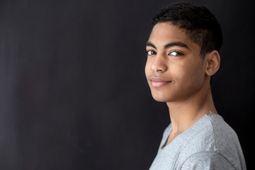 Wall Mural - Portrait of a handsome smiling African American young man on black background. 