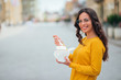 © bnenin - Smiling young woman eating takeout lunch in the city street, copy space.