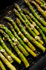 Wall Mural - Grilled green asparagus with garlic, olive oil and aromatic spices on the grill plate, top view