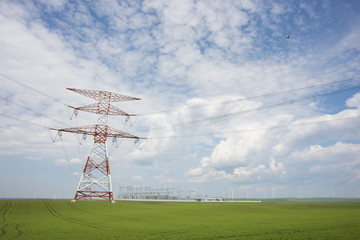 Electricity or  high voltage power lines with electricity station in rural landscape in a summer day