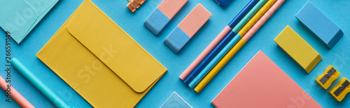 Fotografía panoramic shot of envelope and arranged colorful stationery isolated on blue