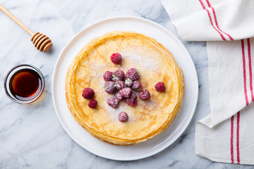 Wall Mural - Thin crepes with raspberry in white plate. Marble background. Top view.