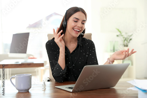 Fotografía Young woman using video chat on laptop in home office