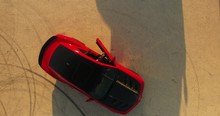 An aerial bird eye following shot of a man walking to a red car An aerial shot of a man walking toward his red race sport red car and open door and getting in