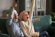 Excited mature couple, man and woman watching football, celebrating victory