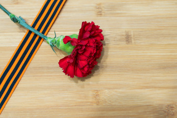 carnation and St. George ribbon on wooden background as greeting cards