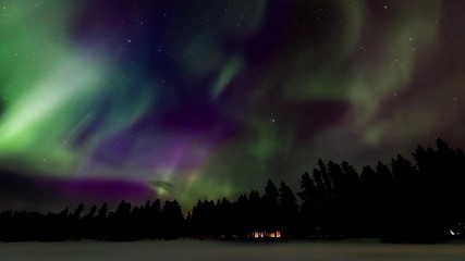 Wall Mural - time-lapse of fast moving vivid green and purple aurora (northern lights) above a cozy cabin and ref