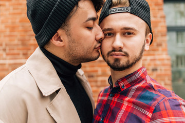 Wall Mural - Gay couple kissing standing on the street. Concepts of same-sex marriage in the world. Man kissing another man's cheek