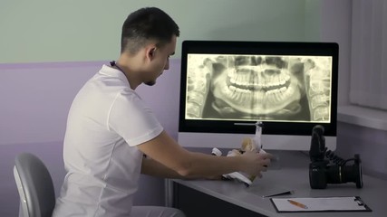 Wall Mural - Dentist is examining gypsym teeth model in his cabinet