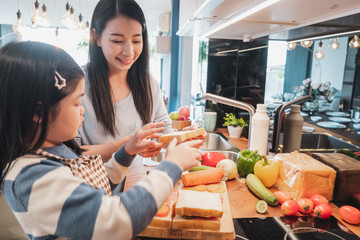 Wall Mural - Asian Mother and her daughter kid cooking food for breakfast in kitchen