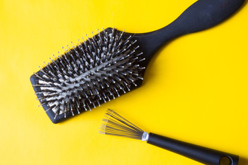 Hairbrush and special tool will help remove tangles and dust stuck between the teeth or bristles. Yellow background. Top view.