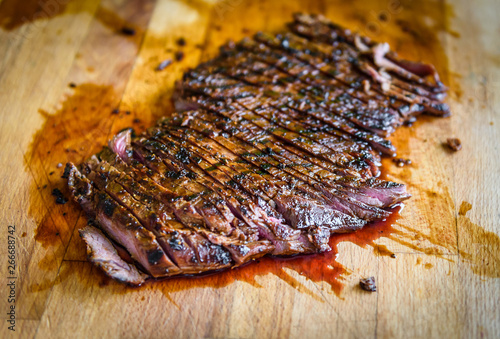 Fotomural Sliced grilled juicy marinated beef flank steak on wooden board.