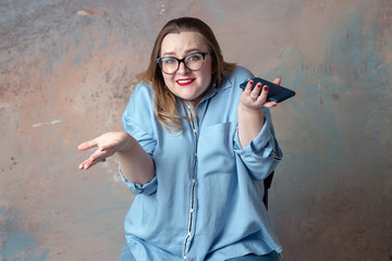 Sticker - Portrait of attractive plus size woman having emotions wonder with the phone in hand isolated over colored background. Concept of emotions. The girl emotionally shows on the phone.