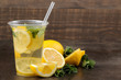 Homemade lemonade with mint and lemon in plastic glasses on a brown background. Refreshing lemonade drink.