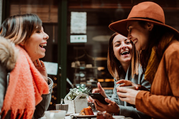 .Group of young friends drinking coffee with cakes in an outdoor cafe in Porto, Portugal. Talking and laughing together. Lifestyle. Travel photography