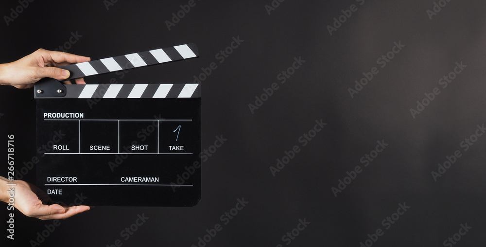 Hand is holding Black clapperboard or movie slate on black background.It have write in number. - obrazy, fototapety, plakaty 