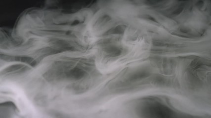 Poster - Close-up of puffs of white smoke floating in the dark. Stock footage. Isolated on black