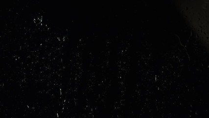 Poster - Transparent water drops flowing down the glass and small white particles floating on the black background. Stock footage. Horizontal view