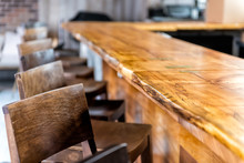 Row Of Empty Wooden Vintage Bar Stools By Counter In Drink Establishment Pub During Day Closeup Of Retro Wood And Nobody
