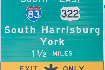 Green road direction sign for exit only to South interstate highway 83 and East route 322 to Harrisburg in Pennsylvania, USA