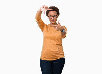 Young beautiful african american woman wearing glasses over isolated background smiling making frame with hands and fingers with happy face. Creativity and photography concept.