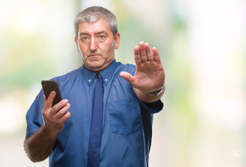 Canvas Print - Handsome senior man texting sending message using smartphone over isolated background with open hand doing stop sign with serious and confident expression, defense gesture