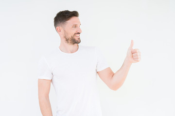 Canvas Print - Young handsome man wearing casual white t-shirt over isolated background Looking proud, smiling doing thumbs up gesture to the side