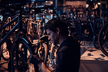 Wall Mural - Diligent attractive mechanic is repairing customer's bicycle at workplace.