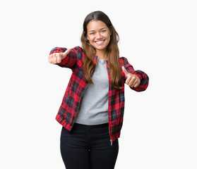 Young beautiful brunette woman wearing a jacket over isolated background approving doing positive gesture with hand, thumbs up smiling and happy for success. Looking at the camera, winner gesture.