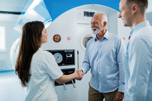 Senior Man And Young Doctor Handshaking In Front Of Hyperbaric Chamber.