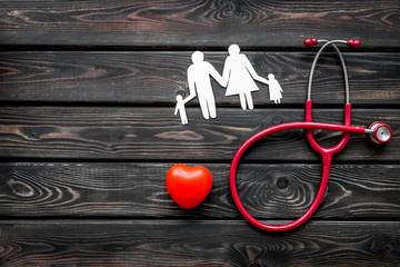 Wall Mural - Stethoscope, heart and paper figure for family doctor set on wooden background top view