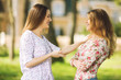 © bokan - Two young women talking and laughing outdoors