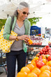 © ML Harris - Happy, middle-aged black African American woman shopping for fresh, organic vegetables produce at farmer's market. Healthy mature lifestyles.