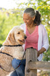 © ML Harris - Happy, mature black African American woman outdoors with her labradoodle pet dog. Active, healthy senior lifestyles.