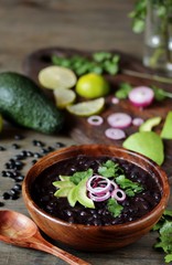 Sticker - black bean soup or stew. Latin American or Mexican cuisine. stewed black beans served with avocado and red onion and cilantro.