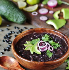 Sticker - black bean soup or stew. Latin American or Mexican cuisine. stewed black beans served with avocado and red onion and cilantro.