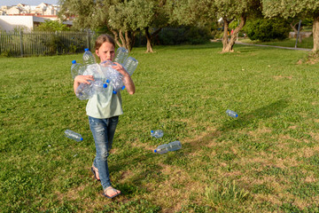 Wall Mural - Young teenage girl recycling plastic bottles.Kid volunteer cleaning up park outdoors.