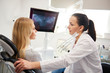 © gpointstudio - Dentist talking to young woman during dental checkup