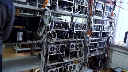 Poster - Cryptocurrency equipment, man in sports suit standing in front of the mining money electronic farm, finance concept. Stock footage. Bitcoin farm with working computer equipment.