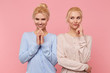 © timtimphoto - Beautiful young blonde twins conceived something interesting and do not want to disclose their secret to anyone. Look mysterious and thoughtful isolated over pink background.
