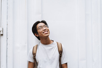 Poster - Smiling young asian man student carrying backpack