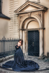 Wall Mural - Princess in lush black dress and tiara praying at entrance to cathedral