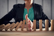 © alphaspirit - Businesswoman stops a chain fall like domino game. Concept of preventing crisis and failure in business.