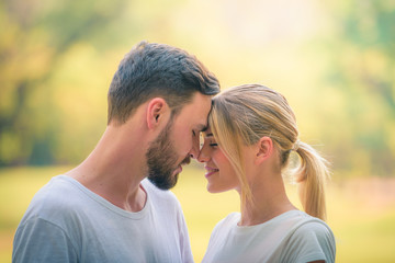 Wall Mural - Portrait image of Young couple enjoying in the park at sunset. Concept romantic and love. Warm tone.