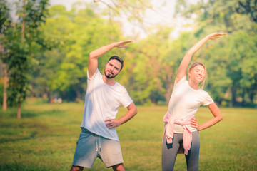 Wall Mural - Portrait of Young couple exercise for health in the park at sunset. Concept sport and love. Warm tone.